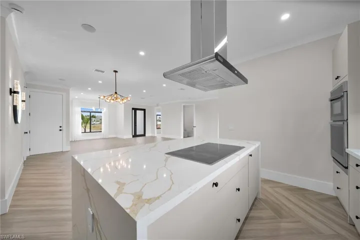 Kitchen with open floor plan, island exhaust hood, black electric cooktop, and recessed lighting