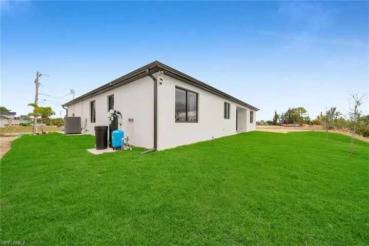 Back of property featuring a lawn, central AC, and stucco siding