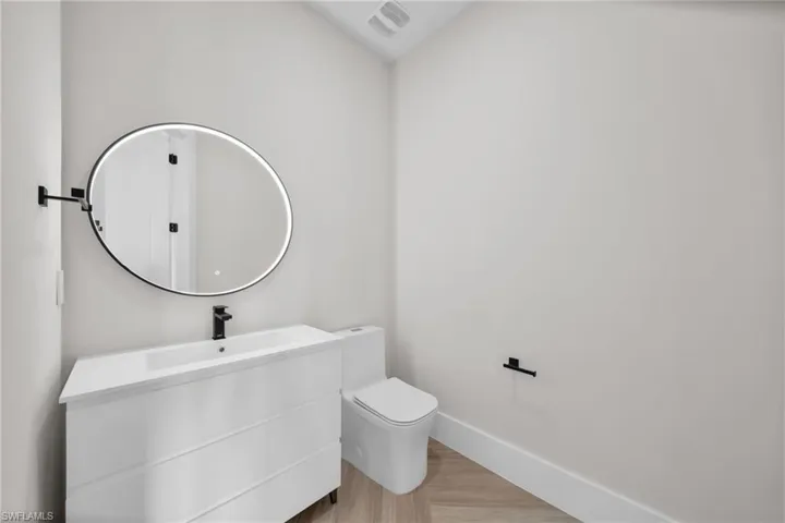 Bathroom featuring visible vents, baseboards, toilet, wood finished floors, and vanity