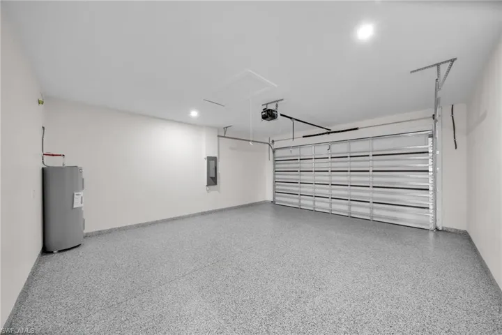 Garage featuring water heater, electric panel, and a garage door opener