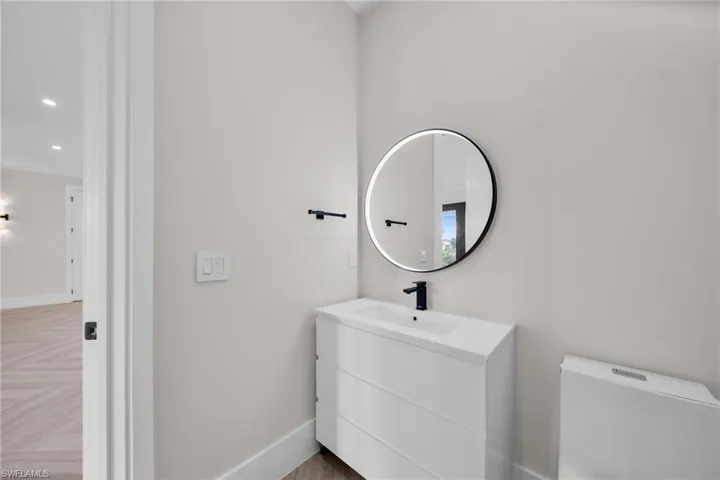 Half bathroom with toilet, recessed lighting, vanity, and baseboards