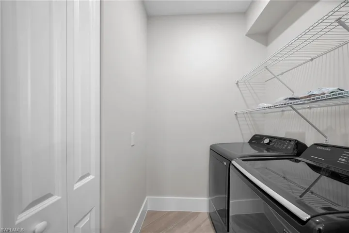 Laundry room with washer and dryer, laundry area, light wood-style flooring, and baseboards