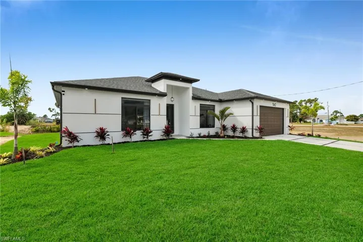 Prairie-style house with an attached garage, a shingled roof, driveway, stucco siding, and a front yard