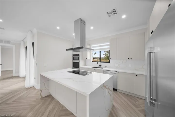 Kitchen with visible vents, island range hood, stainless steel appliances, and a sink