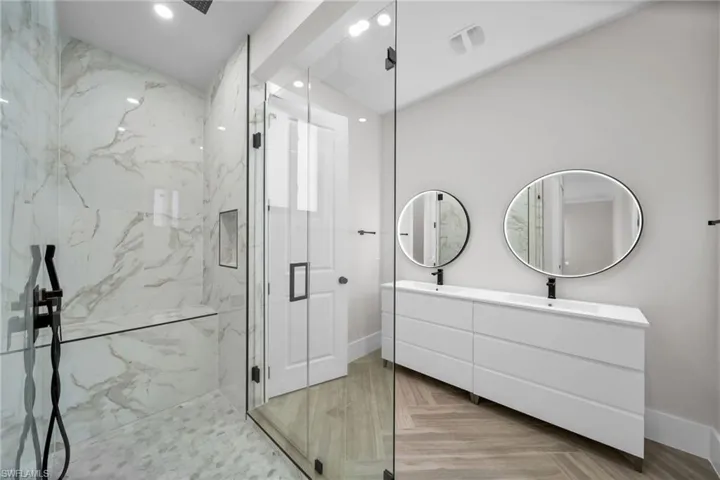 Bathroom featuring double vanity, a marble finish shower, baseboards, a sink, and recessed lighting