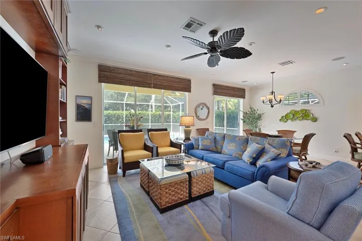 Living area with light tile patterned floors, ornamental molding, recessed lighting, and ceiling fan