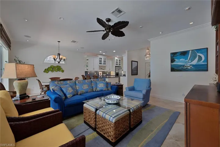 Living room featuring a chandelier, crown molding, ceiling fan, recessed lighting, and tile patterned floors