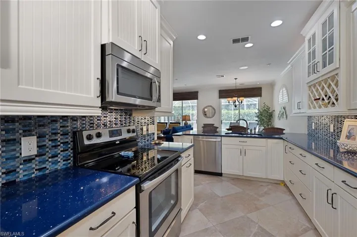 Kitchen with backsplash, appliances with stainless steel finishes, recessed lighting, hanging light fixtures, and a chandelier