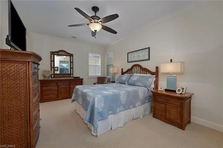 Carpeted bedroom featuring crown molding and ceiling fan