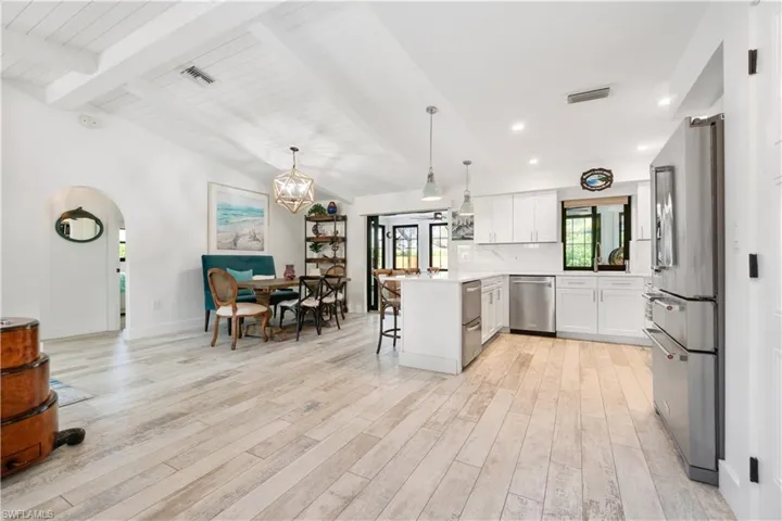 Kitchen with light hardwood / wood-style flooring, white cabinets, stainless steel appliances, and a kitchen bar