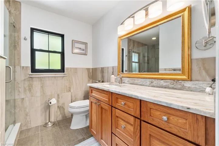 Bathroom with vanity, toilet, and tile walls