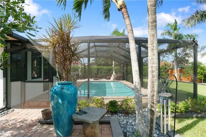 View of pool with a patio area and glass enclosure