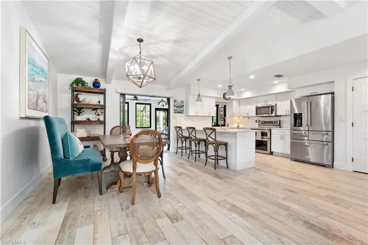 Dining room with light hardwood / wood-style floors, a chandelier, and vaulted ceiling with beams