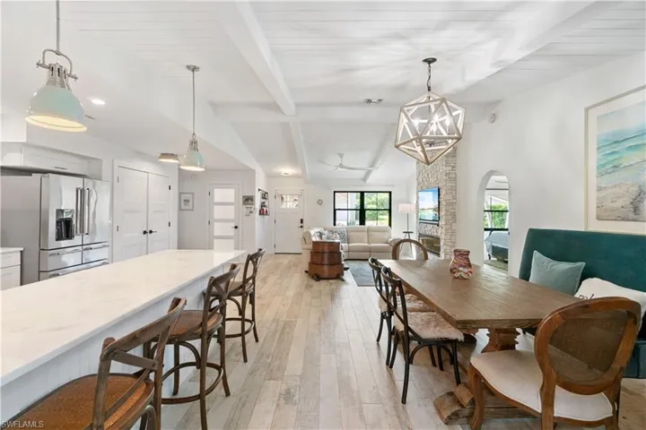 Dining space featuring vaulted ceiling with beams, a chandelier, and light wood-type flooring