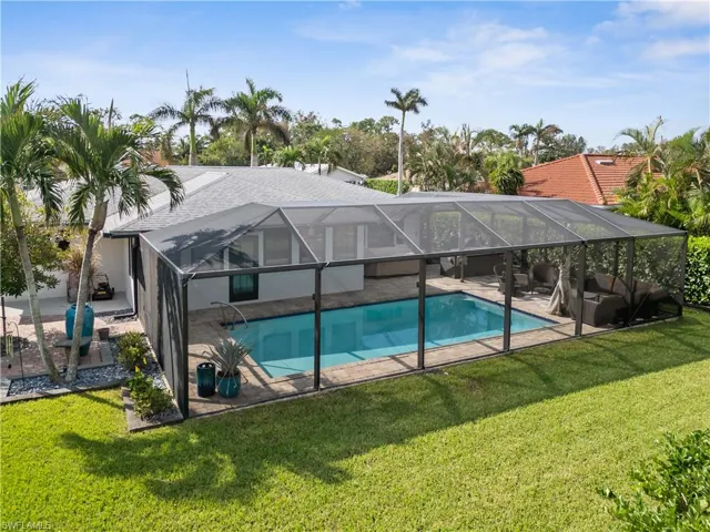 View of pool with a yard, a patio, and glass enclosure