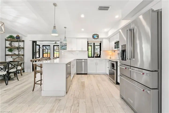 Kitchen with a healthy amount of sunlight, a breakfast bar, appliances with stainless steel finishes, and white cabinetry