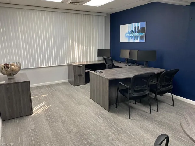Carpeted office space featuring a drop ceiling and baseboards