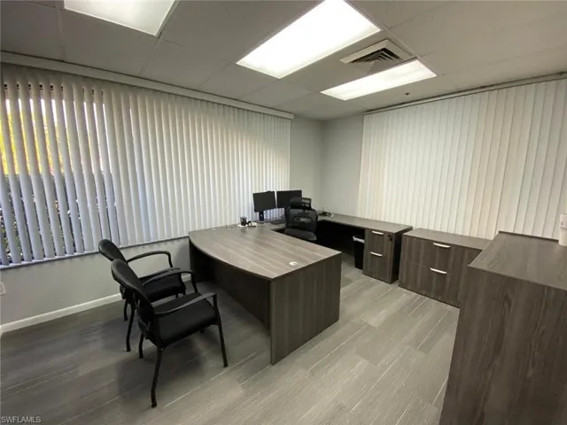 Office area with light wood-style floors, a drop ceiling, and baseboards