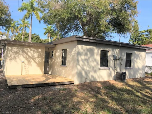 Rear view of house featuring stucco siding, a deck, and a lawn