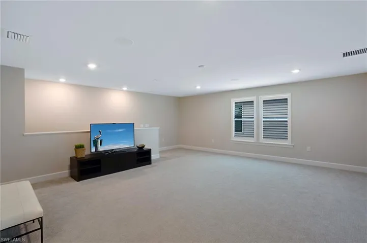 Unfurnished living room with light colored carpet and recessed lighting