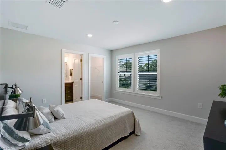 Carpeted bedroom featuring recessed lighting, ensuite bathroom, and a walk in closet