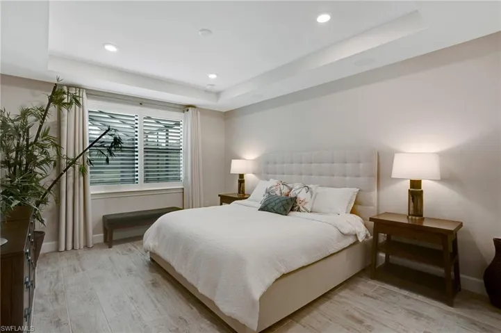 Bedroom featuring a tray ceiling, light wood finished floors, and recessed lighting