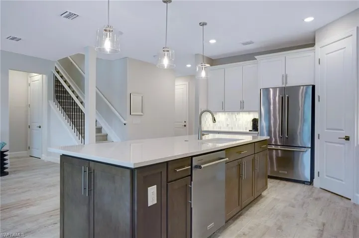 Kitchen featuring stainless steel appliances, light wood finished floors, white cabinetry, recessed lighting, and light countertops