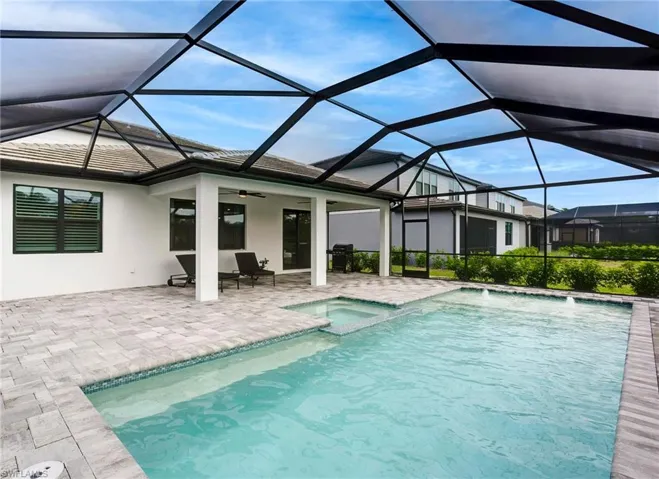 View of swimming pool with a patio, a ceiling fan, a pool with connected hot tub, a grill, and glass enclosure