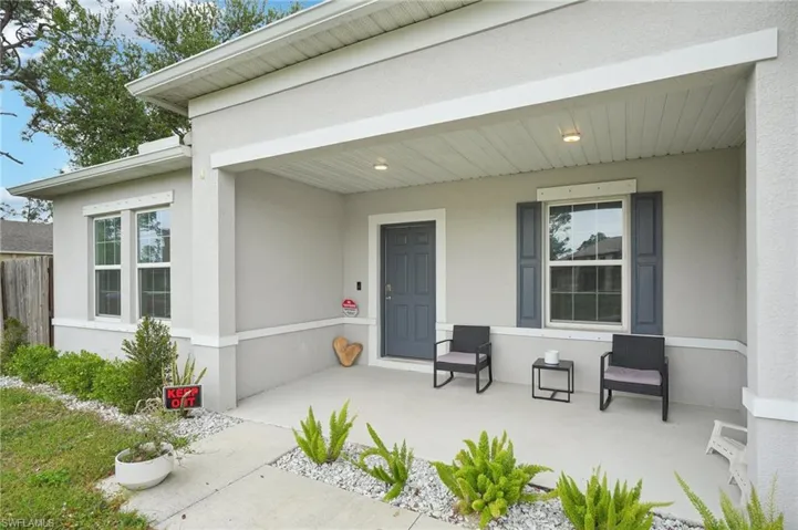 Property entrance with covered porch and stucco siding