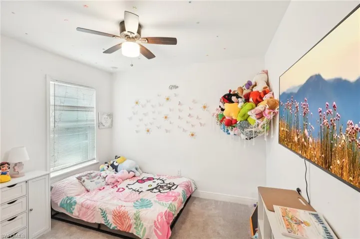 Bedroom with baseboards, light carpet, and a ceiling fan