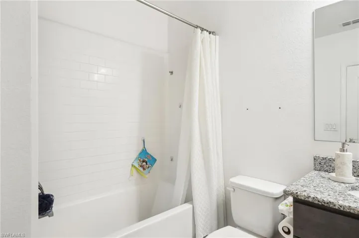 Full bathroom with vanity, toilet, shower / bath combo with shower curtain, and visible vents