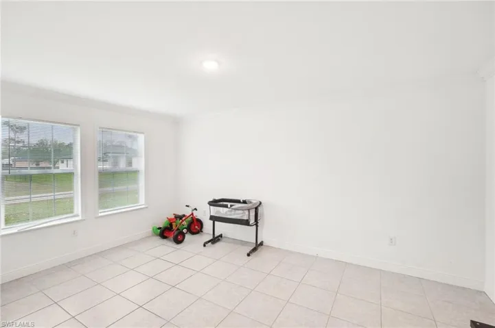 Unfurnished room featuring light tile patterned flooring, baseboards, and ornamental molding