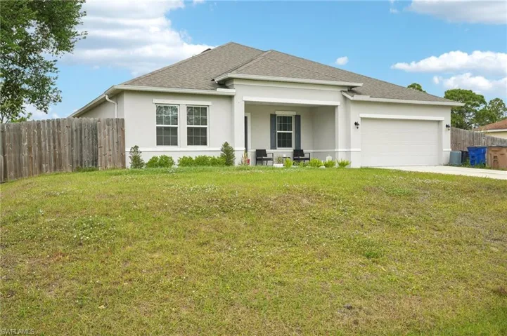 Ranch-style home with stucco siding, a front lawn, fence, a shingled roof, and a garage