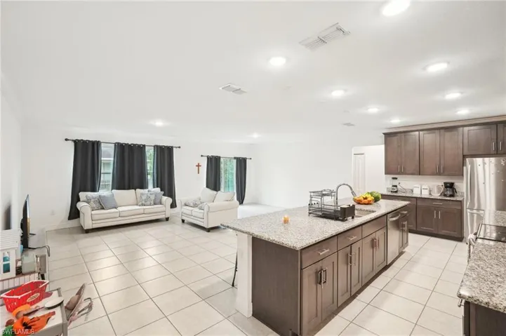 Kitchen with light tile patterned floors, visible vents, dark brown cabinetry, appliances with stainless steel finishes, and a center island