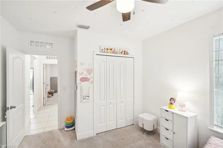 Bedroom featuring light colored carpet, visible vents, and a closet