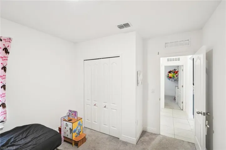Bedroom featuring visible vents, light carpet, and a closet