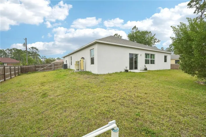 Back of property featuring a yard, cooling unit, a fenced backyard, and stucco siding