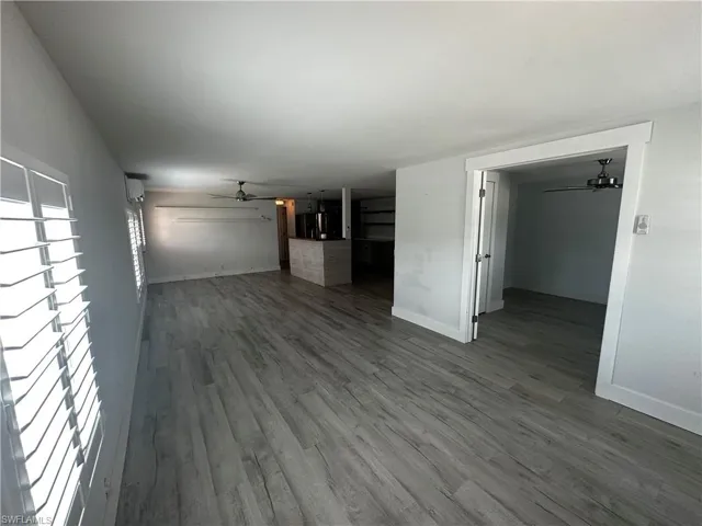 Unfurnished living room with a ceiling fan and dark wood-type flooring