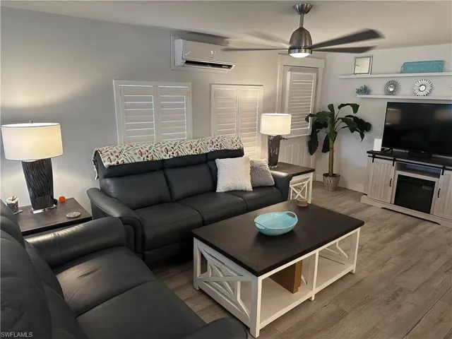 Living room featuring a ceiling fan, a wall mounted mini split, and wood finished floors