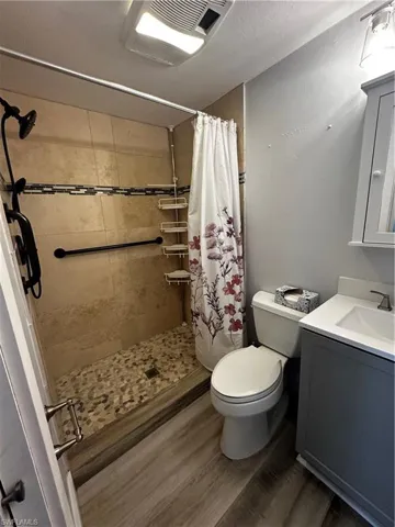 Full bath featuring vanity, a shower stall, and dark wood finished floors