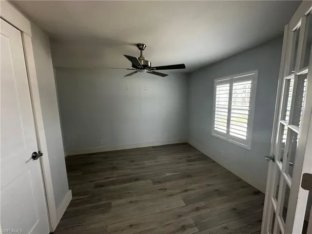 Unfurnished room featuring dark wood-style floors and a ceiling fan