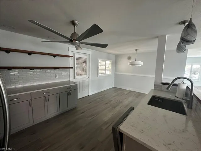 Kitchen featuring pendant lighting, dark wood finished floors, open shelves, fridge, and backsplash