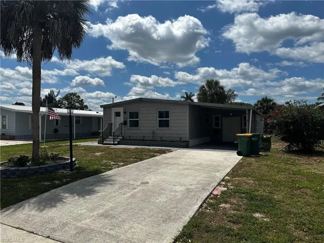View of front facade featuring a front yard, driveway, and an attached carport