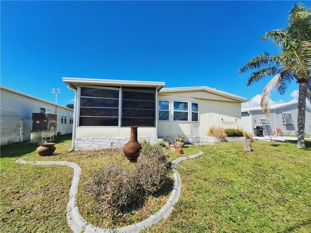 Rear view of house featuring a yard and a sunroom