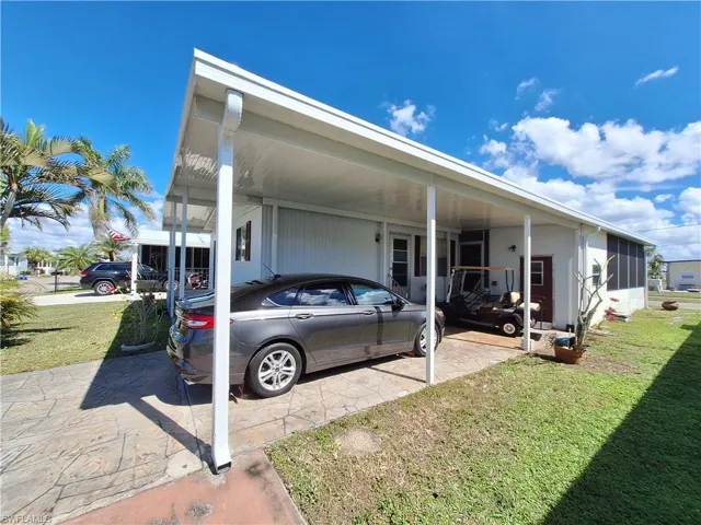 View of side of home with an attached carport and a lawn