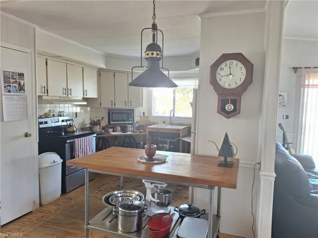 Kitchen with electric stove, a sink, built in microwave, and crown molding