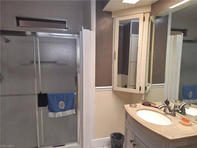 Full bath featuring a wainscoted wall, a stall shower, and vanity