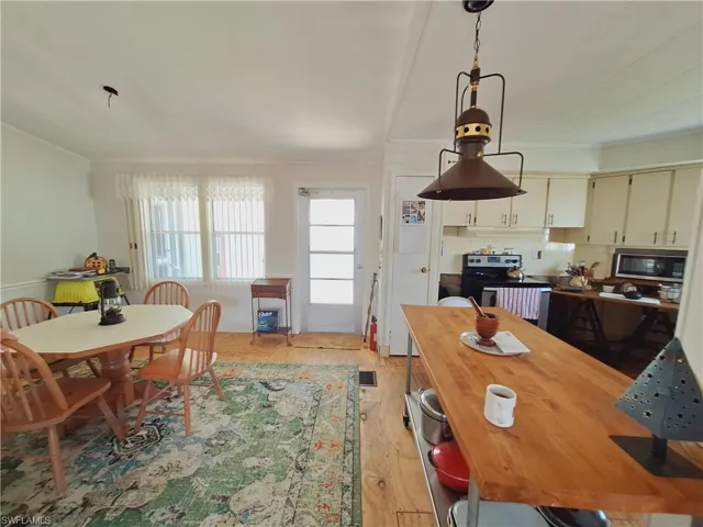 Dining room with visible vents, crown molding, and light wood-style flooring