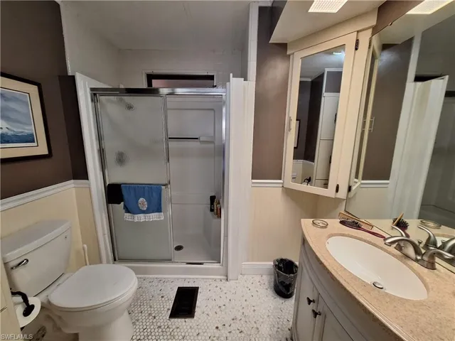 Bathroom featuring visible vents, wainscoting, toilet, vanity, and a shower stall