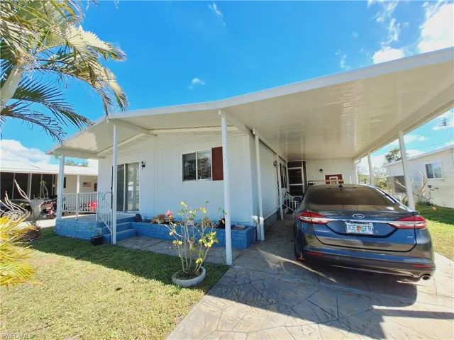 View of parking / parking lot with driveway and a carport